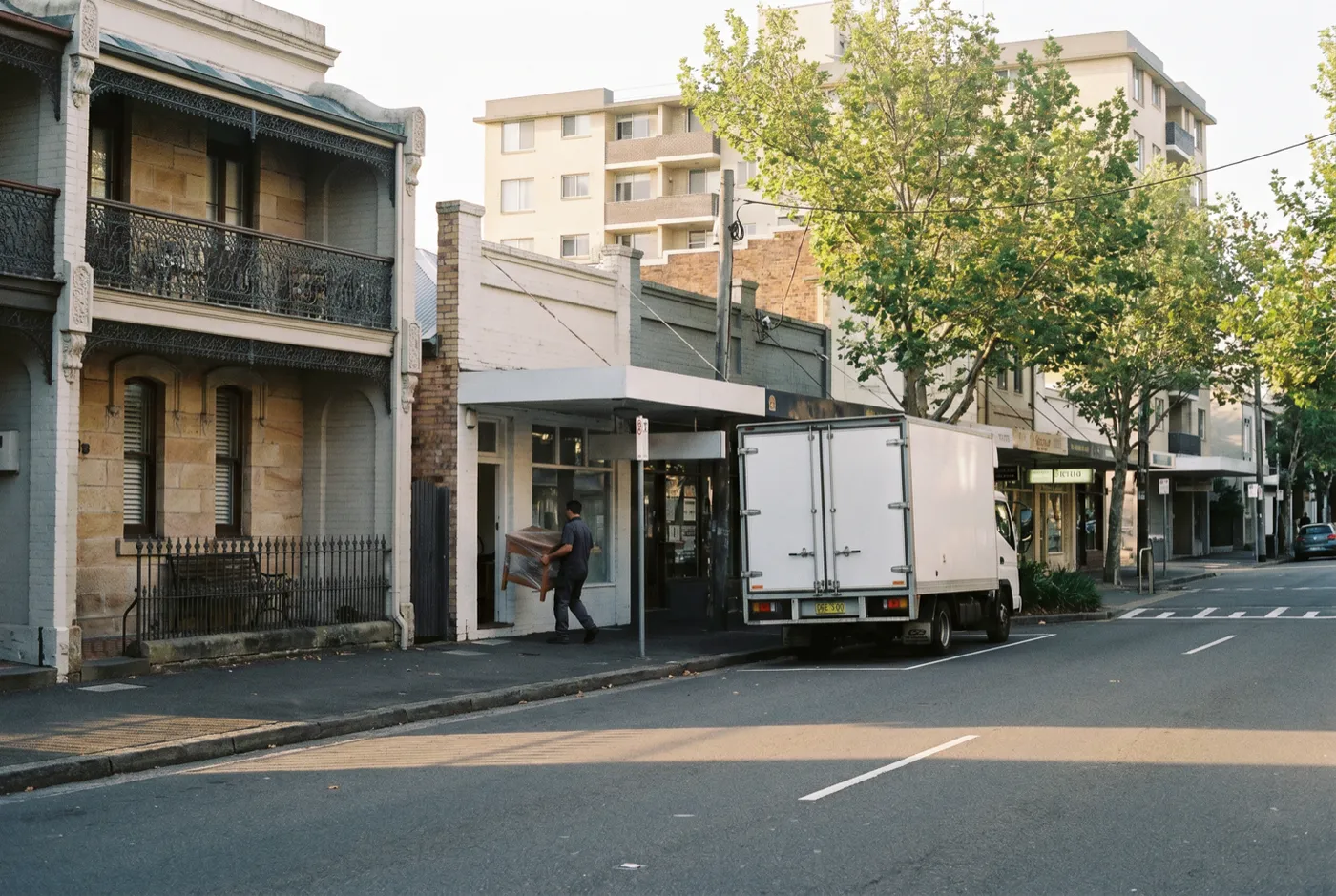Military Road, Neutral Bay at morning: shopfronts with apartment blocks behind, a removal truck in a loading zone